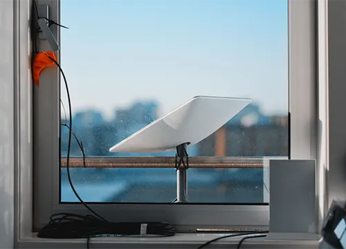 Technician aligning Starlink satellite dish for high-speed internet connection.